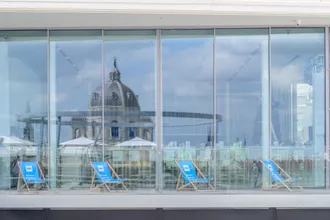 Strandliegen beim BMI Rooftop Talk 2022 bei der MQ Libelle spiegeln sich in den Fenstern des Hauses 
